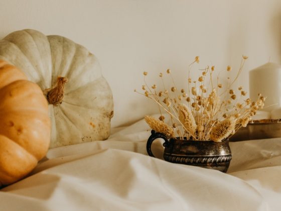 Fireplace mantel decorated with pumpkins, candles, and dried grasses