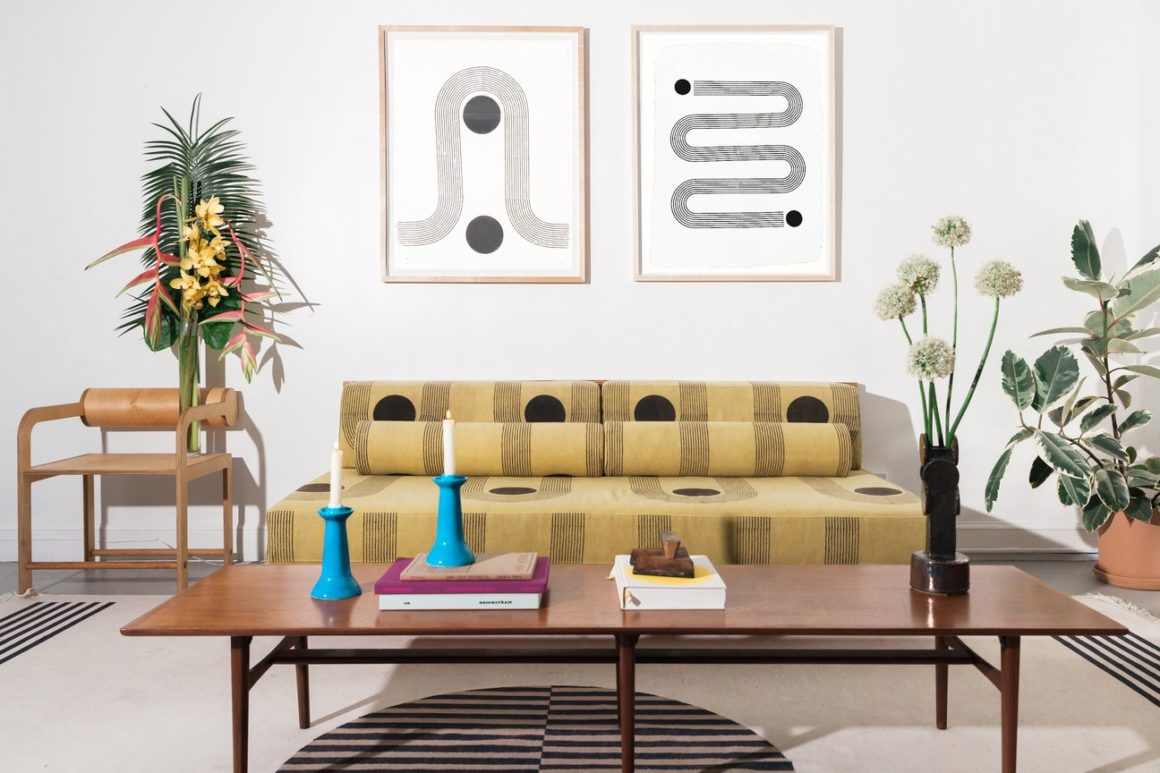 Block Shop Textiles graphic wall art hangs on wall with graphic printed couch in foreground in living room setting.