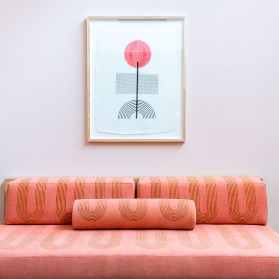 Block shop textiles print hanging on wall with printed fabric covered couch in foreground.